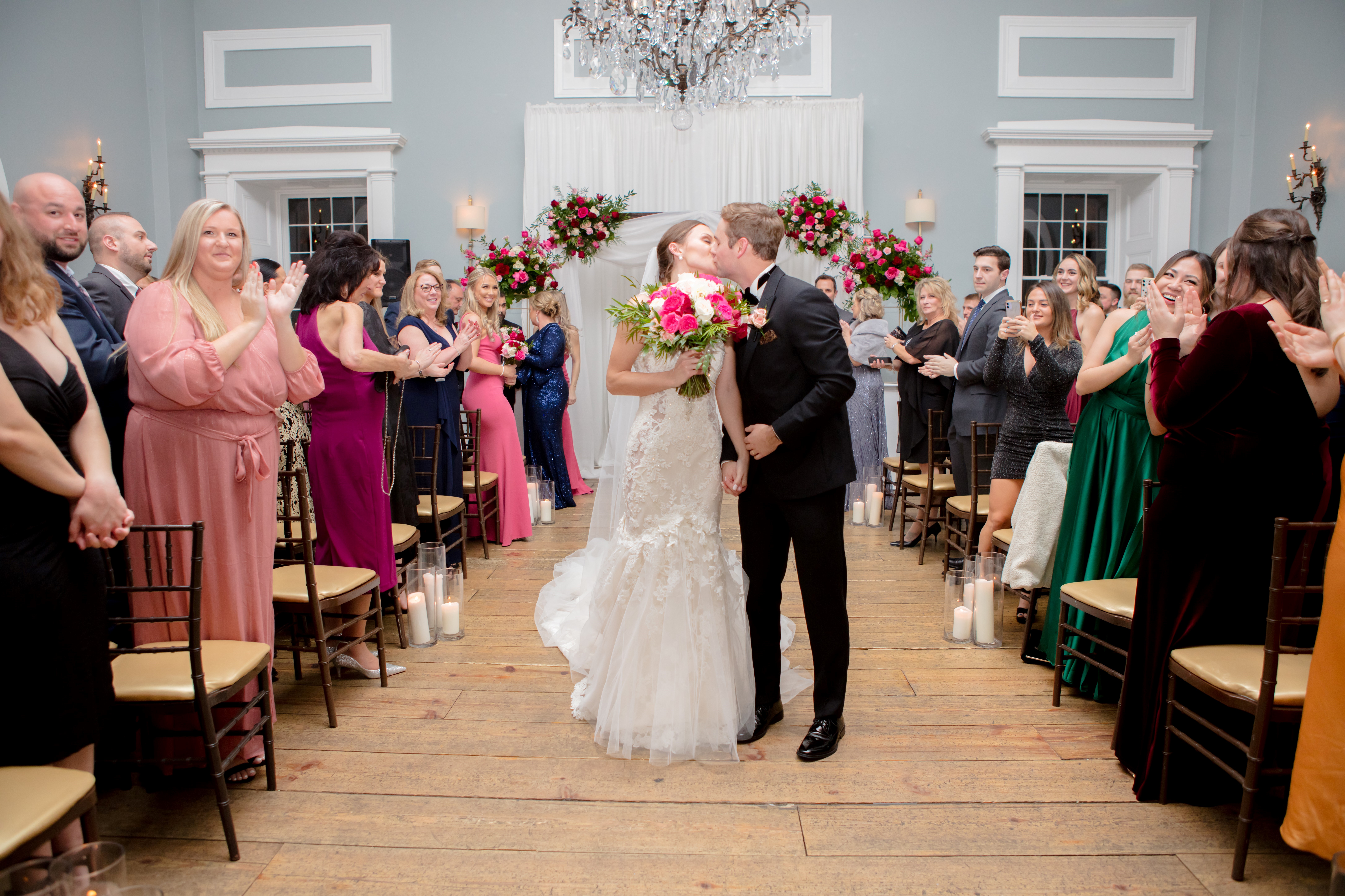 Newly married couple kissing as wedding guests celebrate