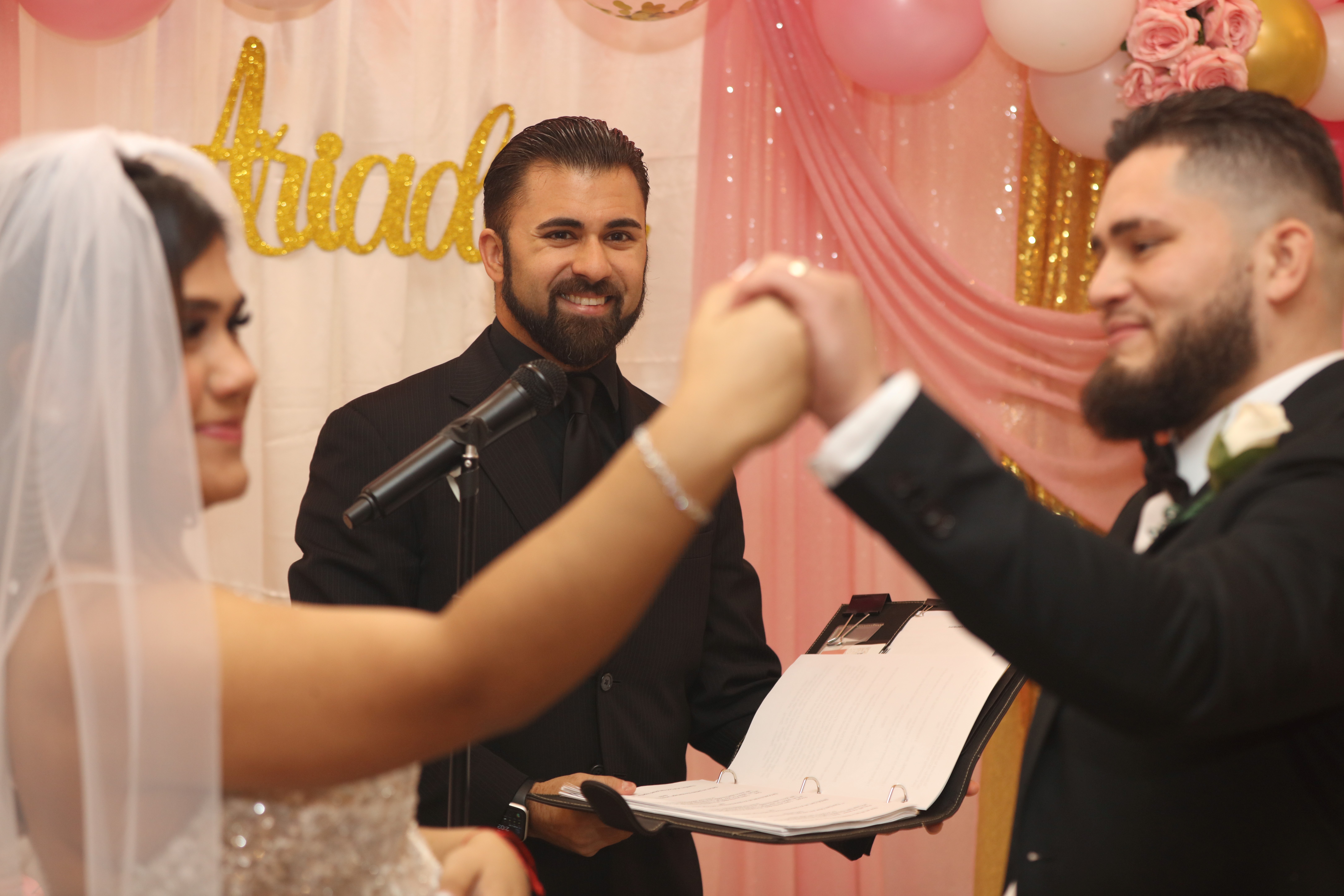 Wedding officiant smiling with a couple at their ceremony