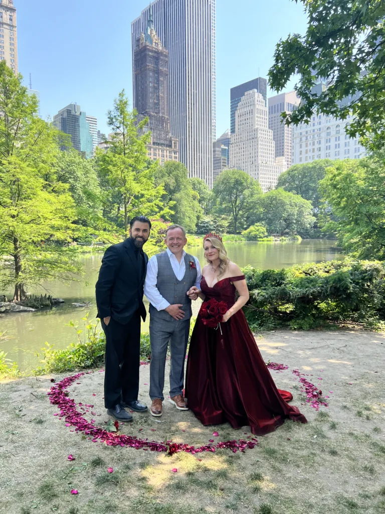 happy couple standing surrounded by rose petals in Central Park New York overlooking the city and a lake