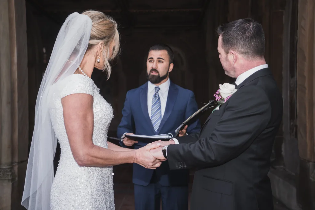 officiant reading wedding vows to couple holding hands in Central Park